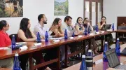 Un grupo de profesionales de la salud y residentes de Medicina Familiar participan en una mesa de trabajo durante el Gran Simposio de Medicina Familiar en la Javeriana Cali. Sentados alrededor de una mesa en forma de “U”, conversan y toman apuntes mientras trabajan colaborativamente. Sobre la mesa hay botellas de agua, portátiles y cuadernos. Al fondo se observan fotografías de comunidades rurales, que acompañan este espacio académico de reflexión y actualización clínica.
