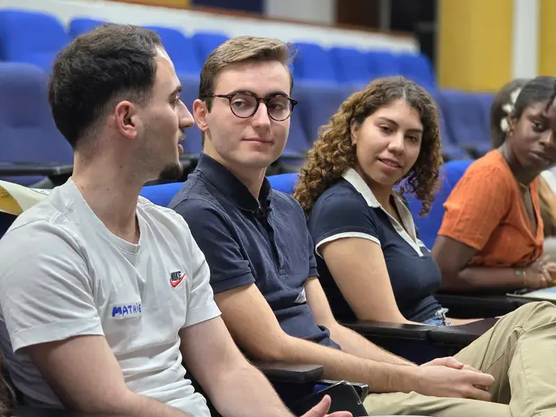 Estudiantes internacionales sentados en el auditorio mientras escuchan las palabras del rector